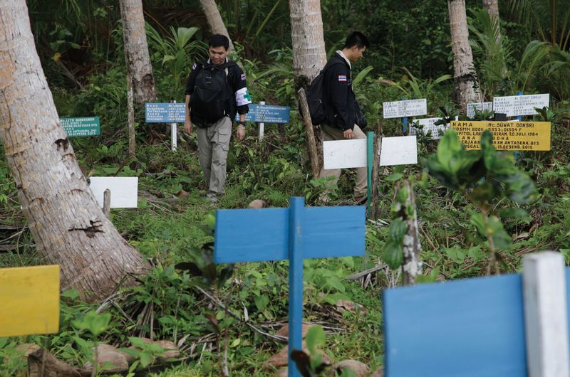 Thai officials inspect the graves of fishermen.