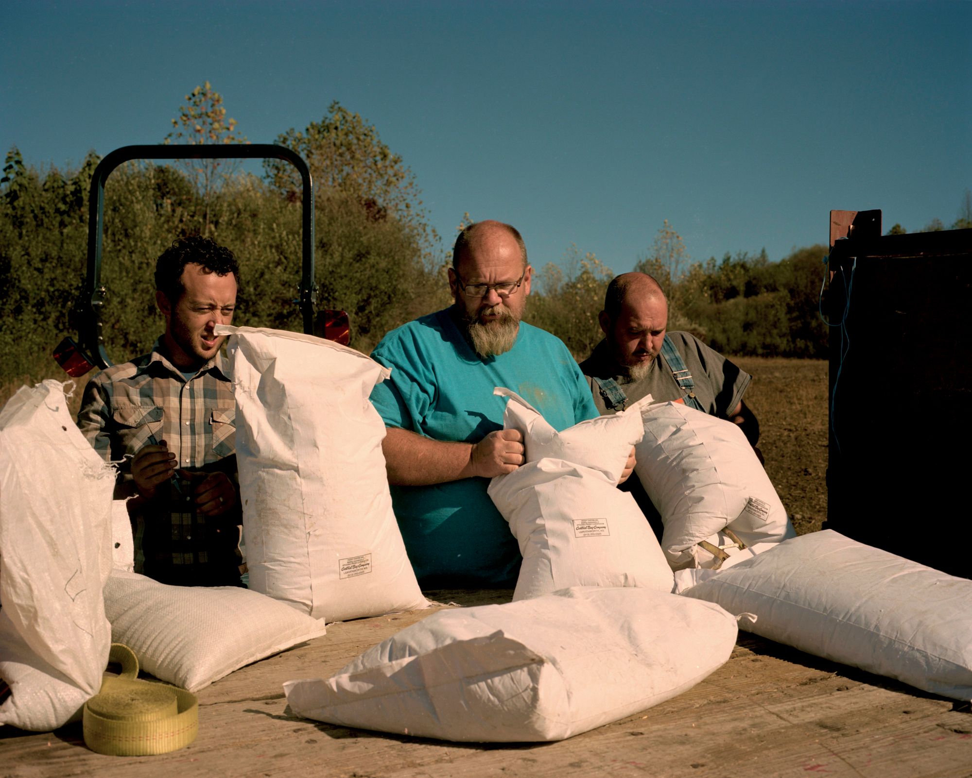 Ben Gilmer, James Russell and Wilburn Jude unload sacks of grain.