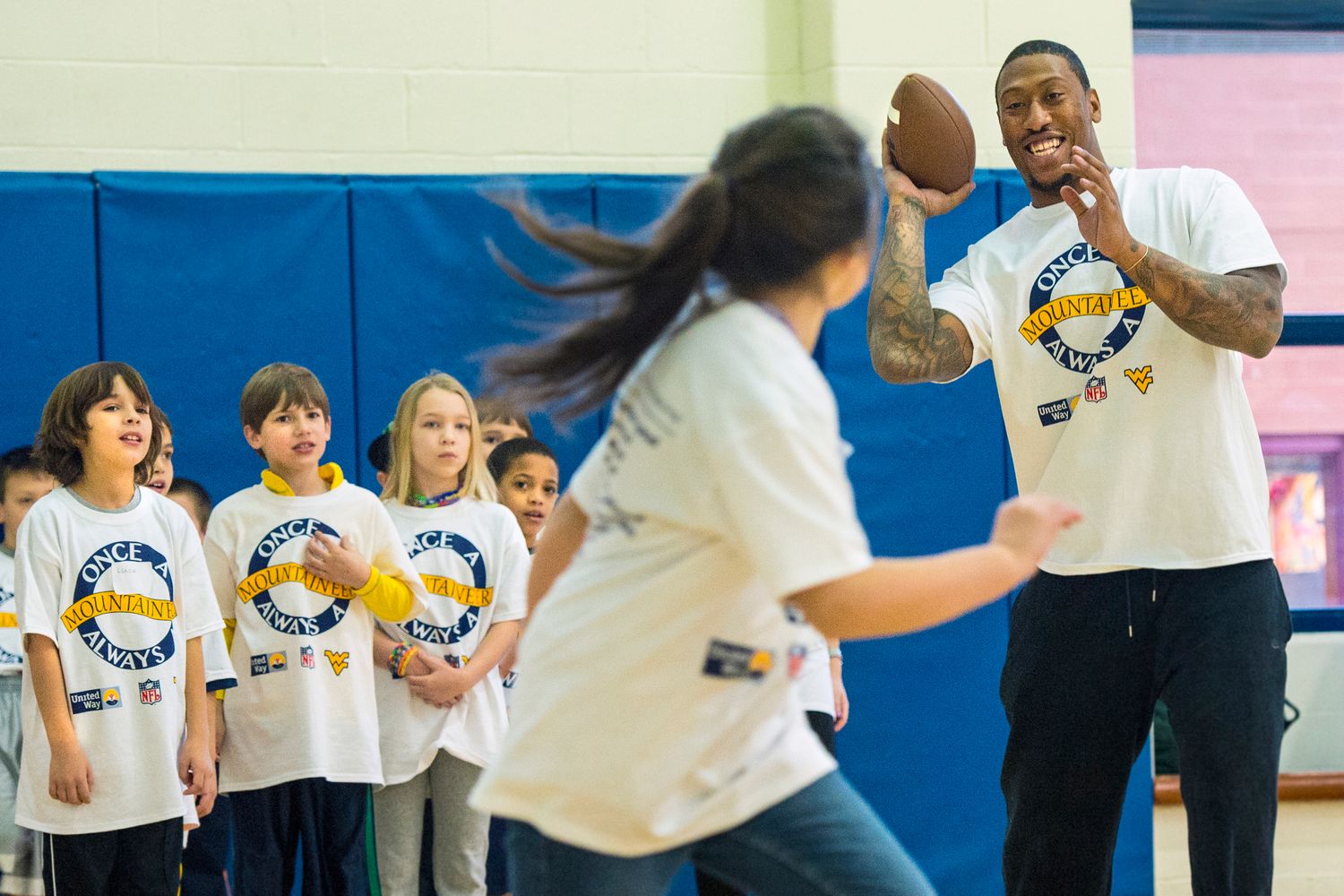 Bruce Irvin plays football with children.