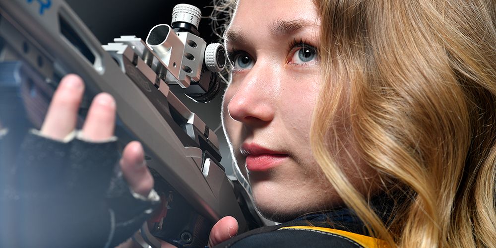 Verena Zaisberger holds a competitive rifle in her hand while looking off frame.