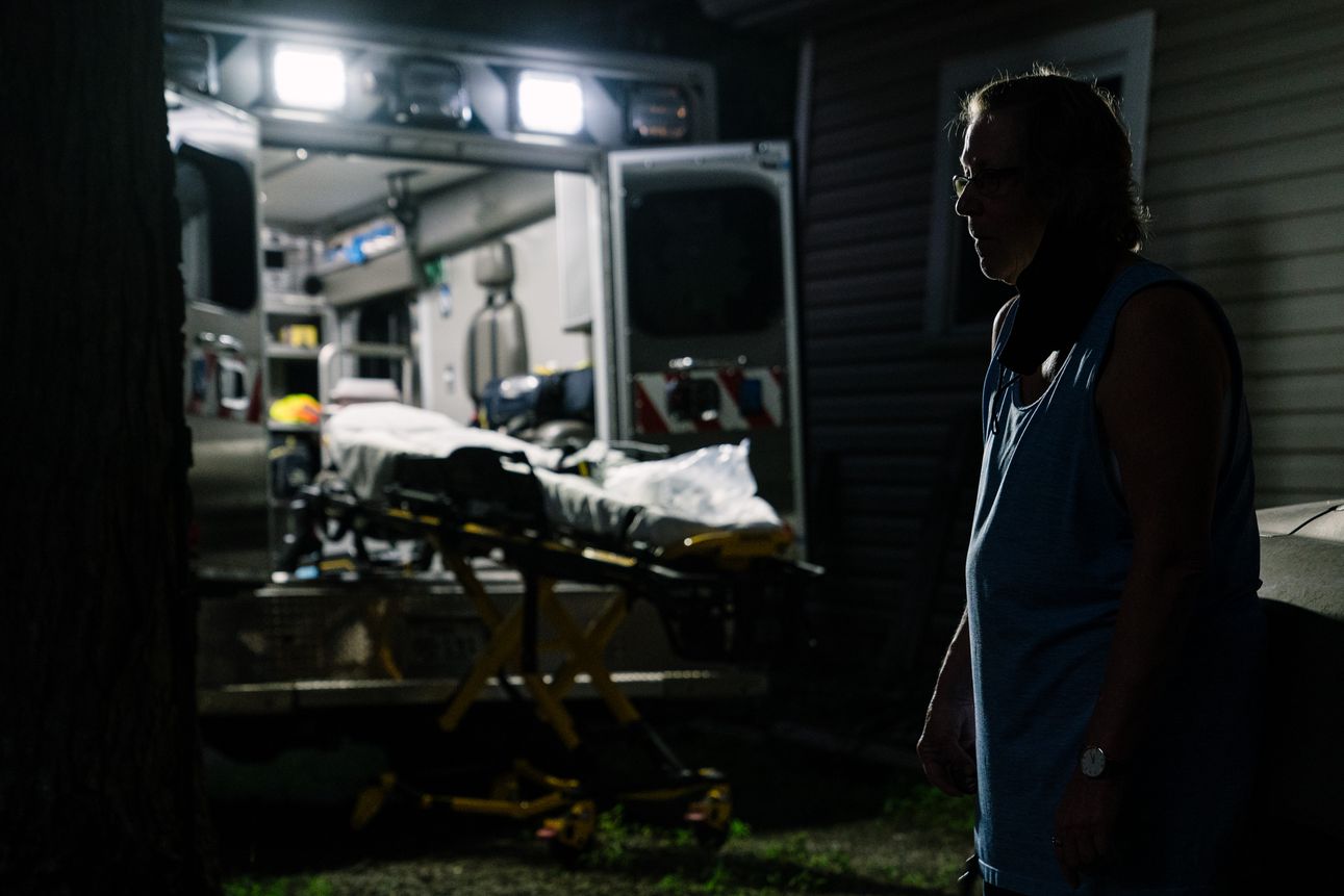 The relative of a deceased man believed to have been infected with COVID-19 stands near the ambulance waiting to take her relative to a local funeral home on August 6th, 2020. 