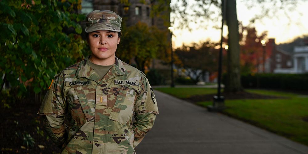 Michelle Sieminski poses in her camouflage Army uniform near Stewart Hall at sunset.