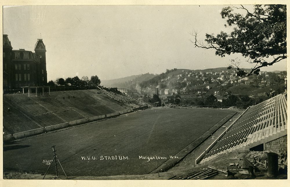 Mountaineer field is empty with Woodburn Hall off to the side and a hill of homes in the background.