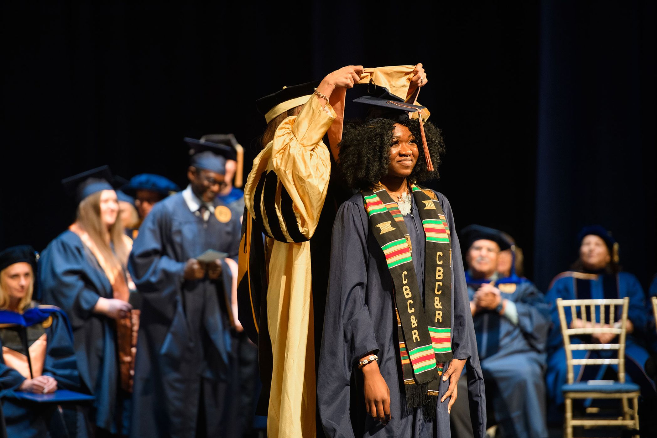 woman receives hood during graduation ceremonies