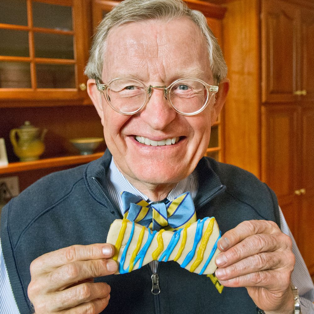 Gordon Gee holds up a cookie in the shape of a bow tie.