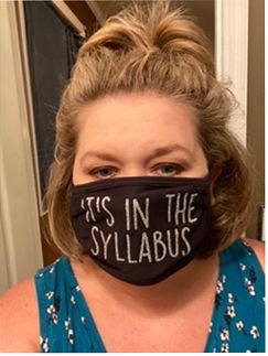 Woman wearing black face mask that says "It's in the Syllabus."