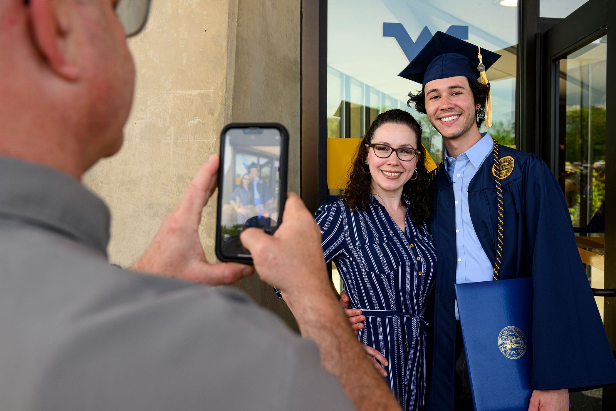 person takes picture of woman, graduate