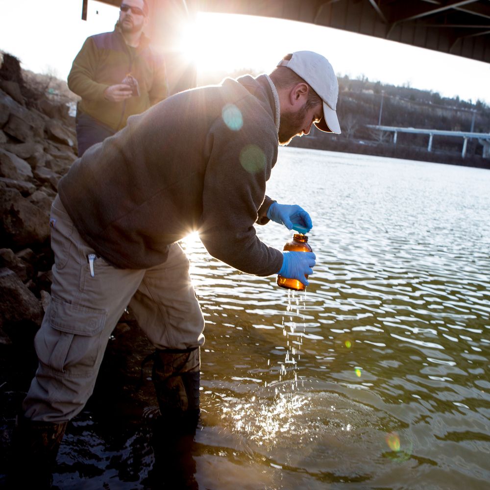 A scientist collects a water sample from a river in Charleston.