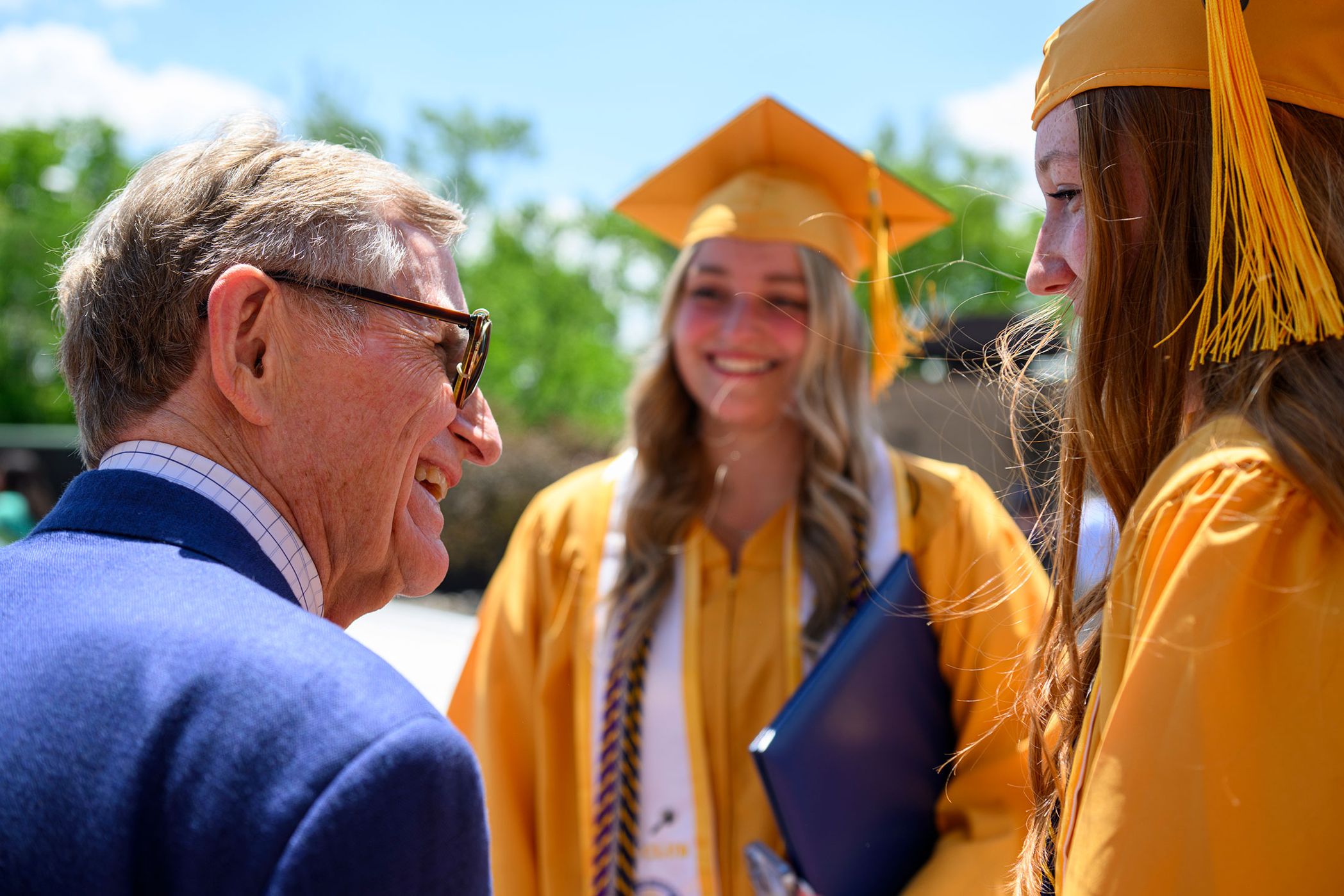 man greets young women in graduation regaliz