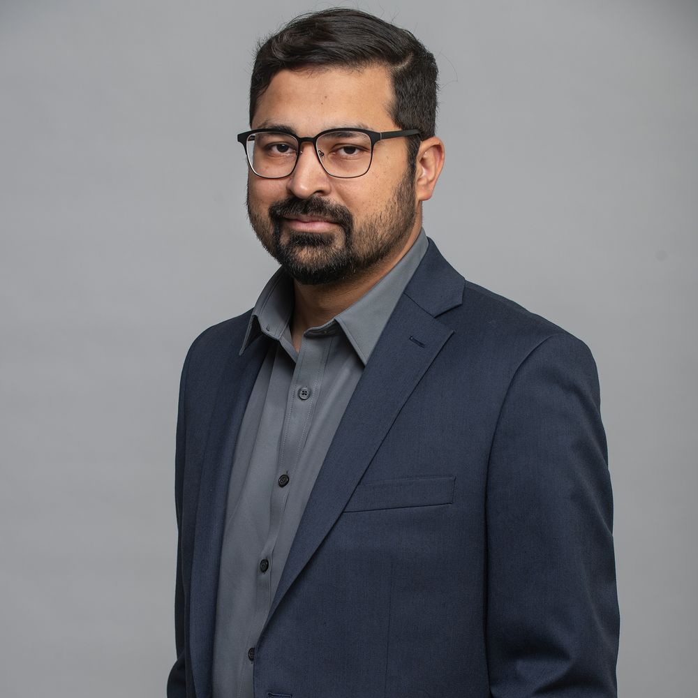 Portrait of Safi Khan against a gray backdrop.