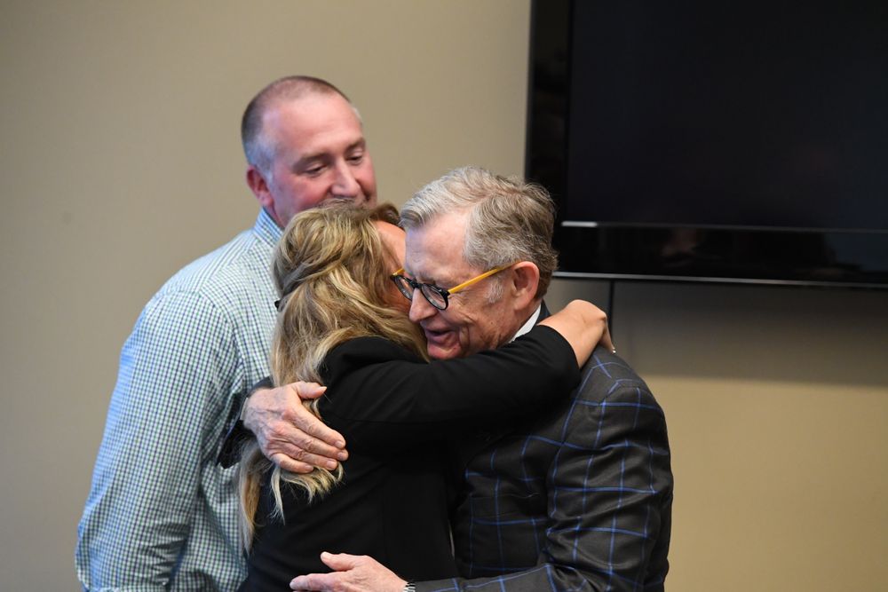 President Gee embraces Kim Burch while her husband TJ looks on.