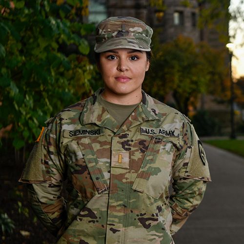 Michelle Sieminski poses in her camouflage Army uniform near Stewart Hall at sunset.