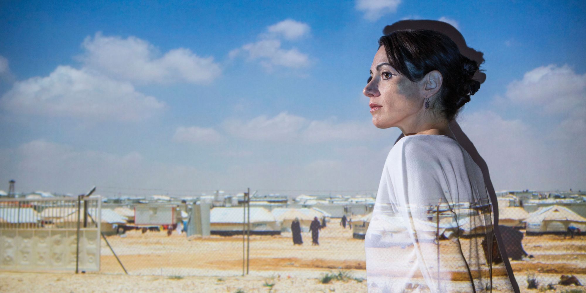Karen Culcasi stands in front of a photo she took of a refugee camp in Jordan.