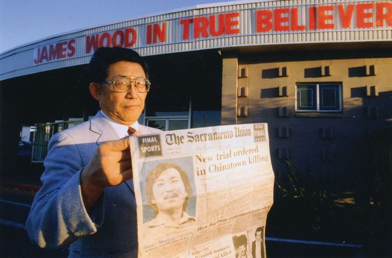 K.W. Lee holds up newspaper from the Sacramento Union describing the release of a falsely accused Korean man.