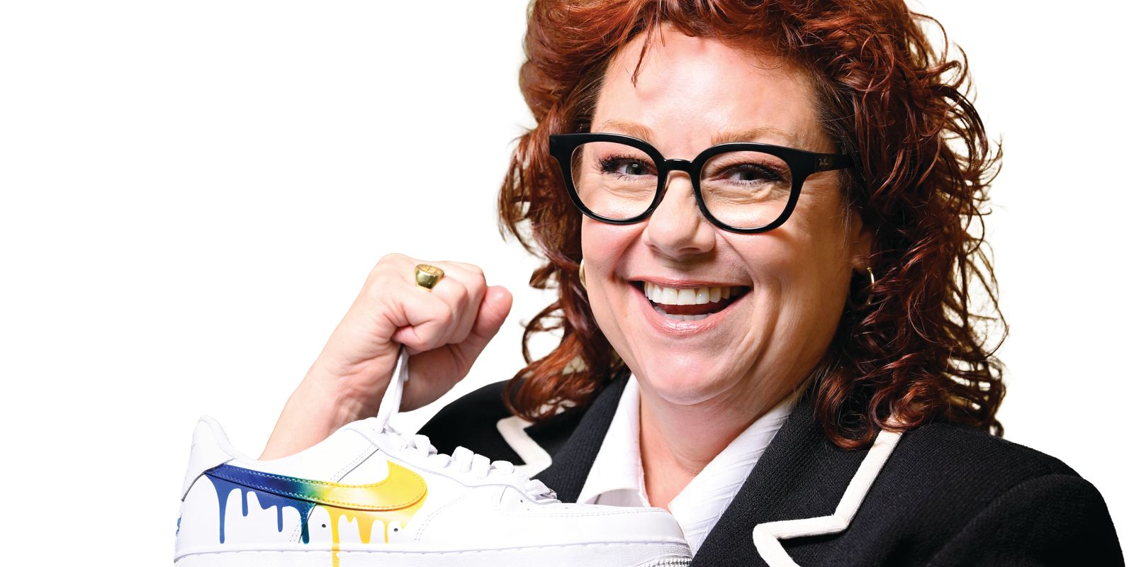 woman, red hair, glasses, holds sneaker with dripping gold and blue paint