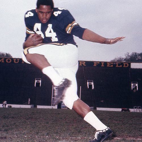 Jim Braxton poses in his jersey #44 while holding a football.