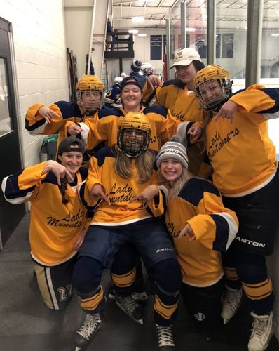 WVU women's ice hockey team makes Horns Down sign outside of rink.