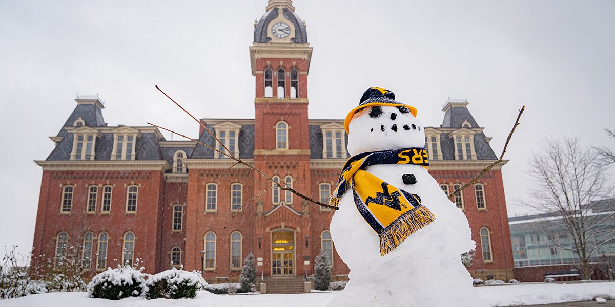 A snowman in front of Woodburn Hall wears a Mountaineer scarf and hat. 