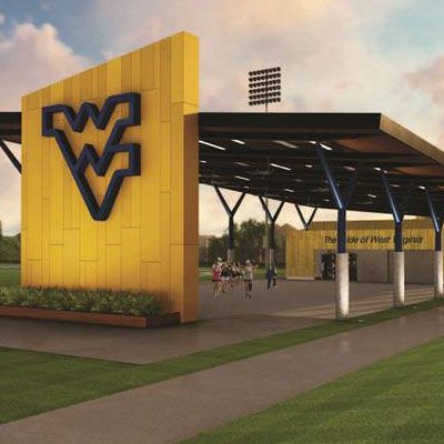 Green grass, with yellow wall and flying blue WVU sign